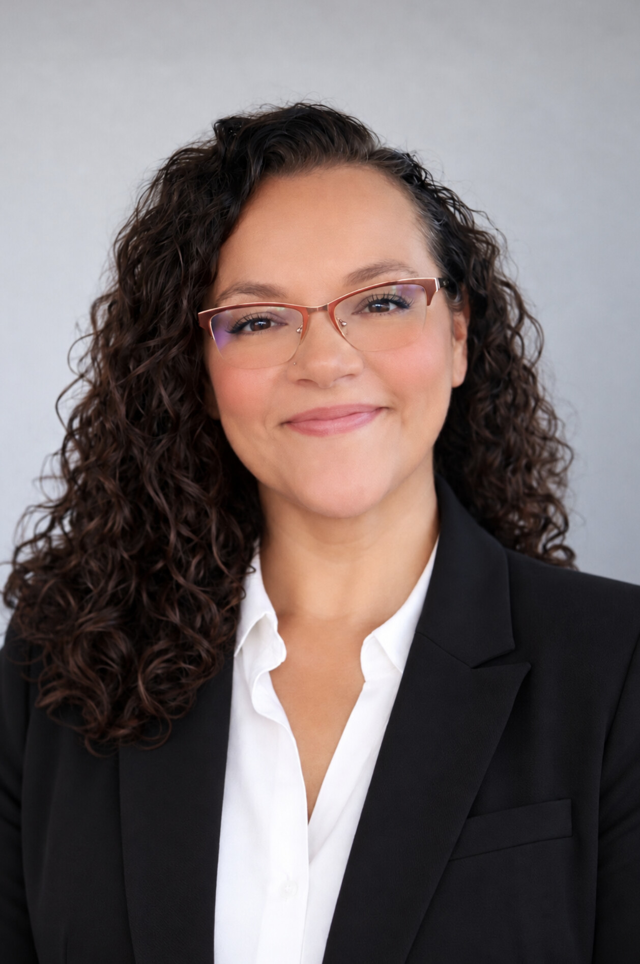 Kat La Reina smiling in a black blazer and white blouse